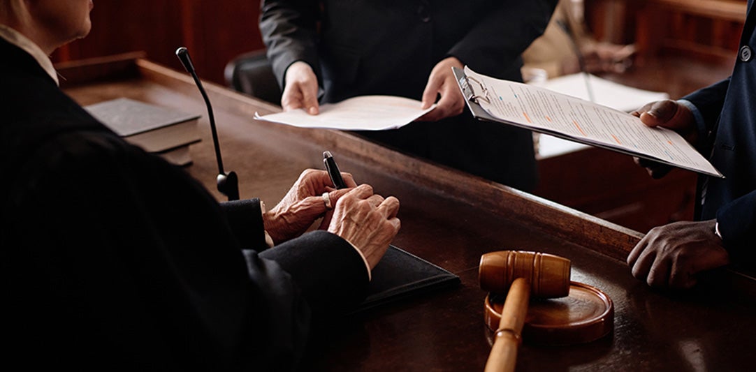 Judge reviewing documents with attorneys in a courtroom.