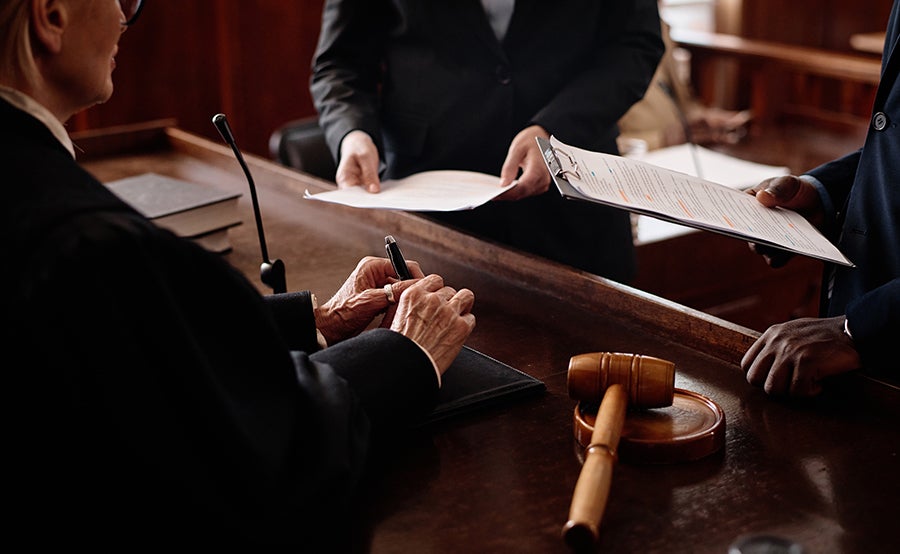 A judge's sign documents at a courtroom bench, while others present papers